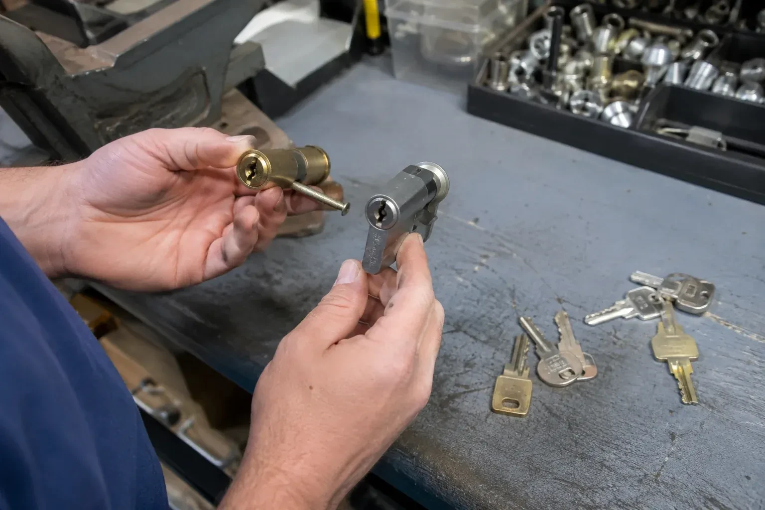 Hands comparing detached lock cylinders beside loose keys on a workbench. — Broken Key Extraction, Norfolk County